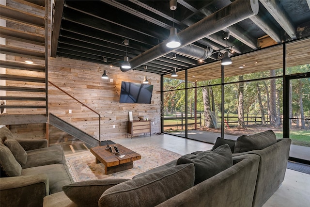 living room with concrete flooring, a wall of windows, and wooden walls