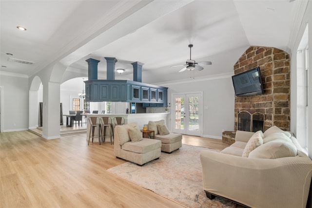 living room featuring ceiling fan with notable chandelier, light wood-type flooring, lofted ceiling, and crown molding