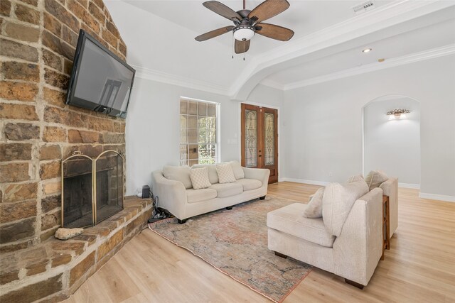 living room featuring ceiling fan, light hardwood / wood-style flooring, a fireplace, and ornamental molding