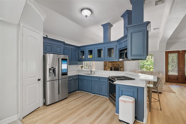 kitchen with appliances with stainless steel finishes, light hardwood / wood-style floors, a breakfast bar, kitchen peninsula, and sink