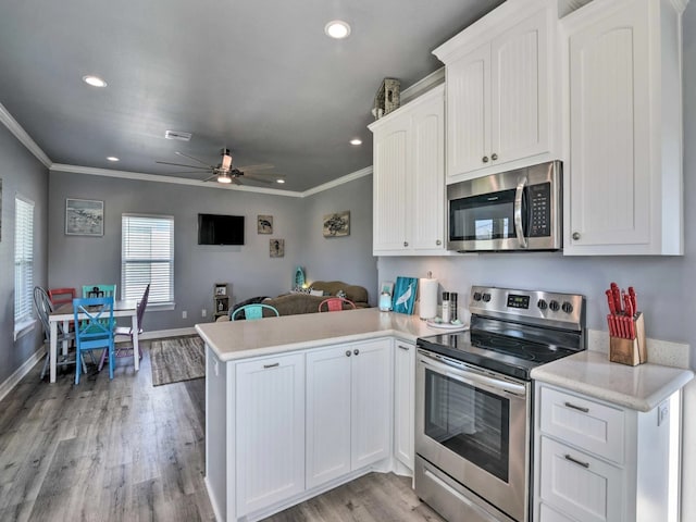 kitchen with white cabinetry, kitchen peninsula, stainless steel appliances, and light wood-type flooring