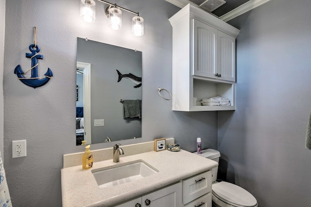 bathroom with vanity, toilet, and crown molding