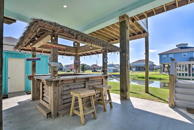 view of patio featuring a water view, a gazebo, and exterior bar