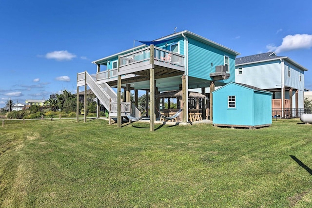 back of house featuring a wooden deck, a lawn, and a shed