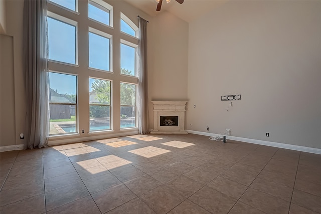 unfurnished living room with ceiling fan, a towering ceiling, and light tile patterned flooring