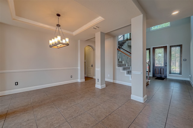 unfurnished room featuring an inviting chandelier, light tile patterned flooring, crown molding, and a tray ceiling