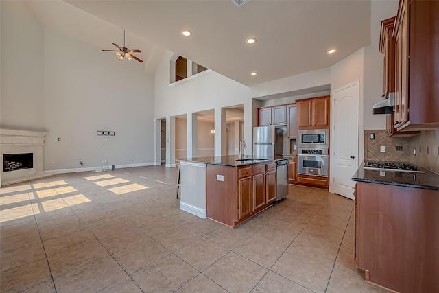 kitchen featuring high vaulted ceiling, a center island with sink, sink, appliances with stainless steel finishes, and a breakfast bar area