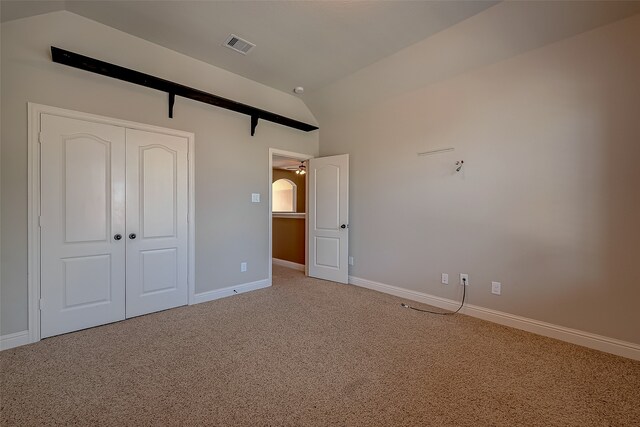 unfurnished bedroom with carpet flooring, a closet, and vaulted ceiling