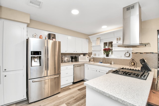 kitchen featuring white cabinets, island range hood, light hardwood / wood-style flooring, appliances with stainless steel finishes, and backsplash