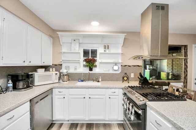 kitchen featuring stainless steel appliances, sink, island range hood, white cabinetry, and light hardwood / wood-style flooring