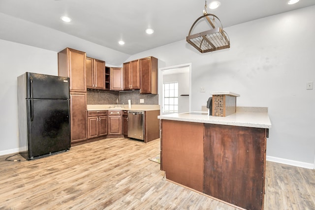 kitchen featuring black fridge, kitchen peninsula, stainless steel dishwasher, light hardwood / wood-style flooring, and backsplash