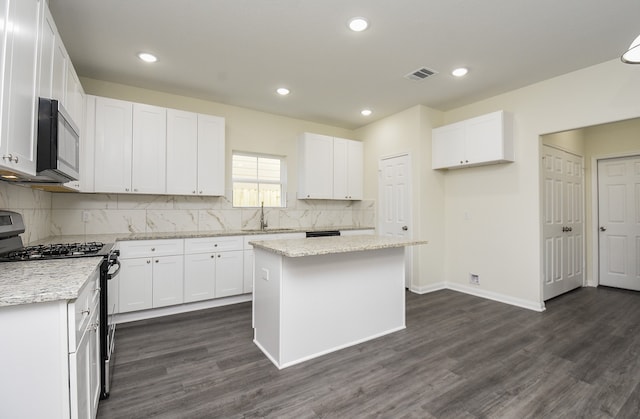 kitchen featuring gas range oven, dark wood-type flooring, white cabinetry, and a center island