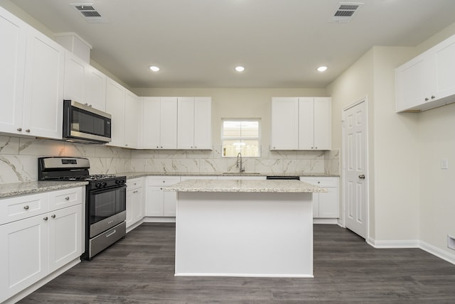 kitchen with stainless steel appliances, dark hardwood / wood-style floors, and white cabinetry