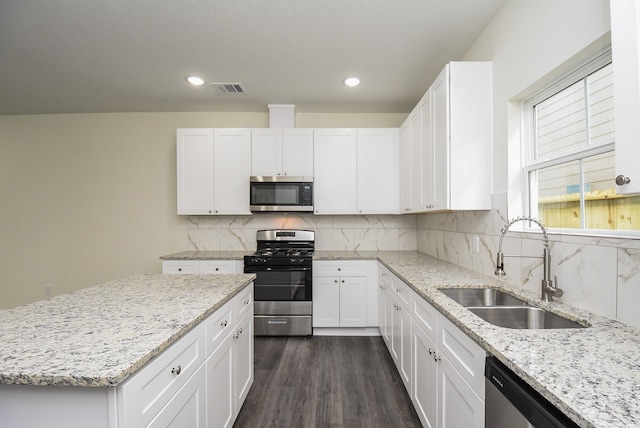 kitchen with light stone counters, sink, dark hardwood / wood-style flooring, white cabinetry, and appliances with stainless steel finishes