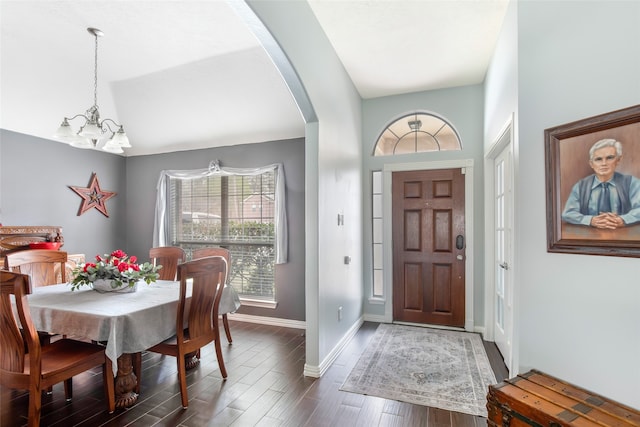 entrance foyer with a notable chandelier, vaulted ceiling, and dark hardwood / wood-style flooring