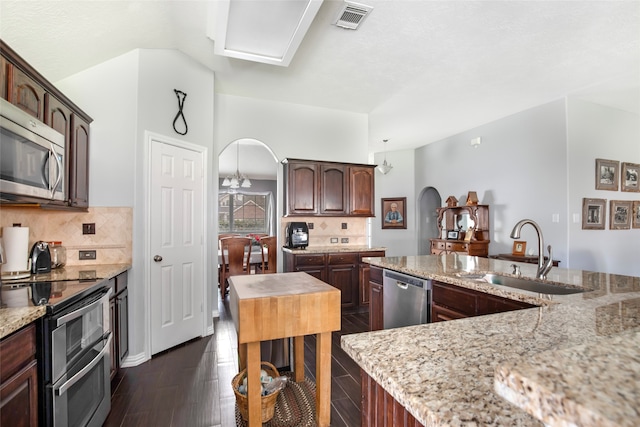 kitchen with a kitchen island, light stone counters, dark hardwood / wood-style floors, stainless steel appliances, and sink