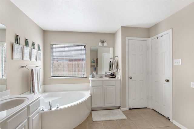 bathroom with tile patterned floors, a washtub, and vanity