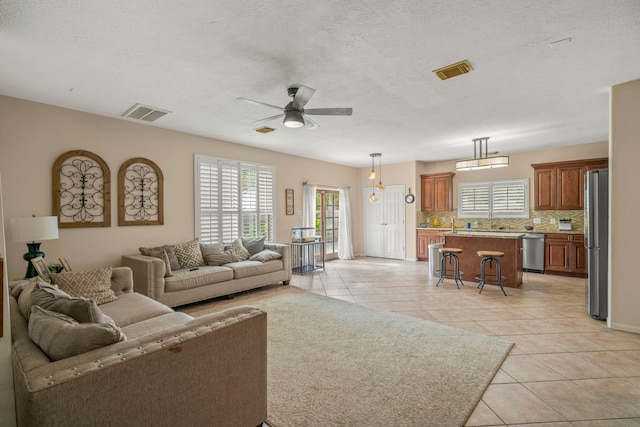 living room with sink, light tile patterned flooring, a textured ceiling, and ceiling fan