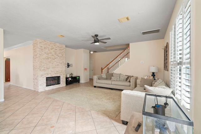 tiled living room featuring ceiling fan and a fireplace