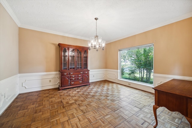 unfurnished dining area featuring a notable chandelier, a textured ceiling, parquet flooring, and ornamental molding