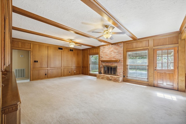 unfurnished living room with a textured ceiling, a healthy amount of sunlight, a fireplace, and light colored carpet