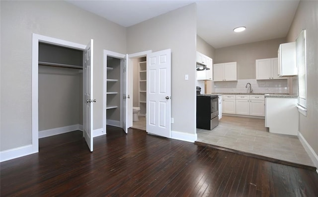 kitchen featuring sink, wood-type flooring, black electric range, white cabinetry, and decorative backsplash