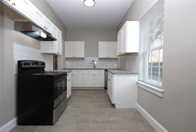 kitchen with light stone counters, black electric range oven, sink, white cabinetry, and decorative backsplash