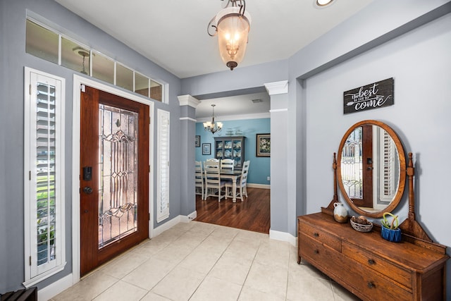 tiled entryway featuring decorative columns and an inviting chandelier