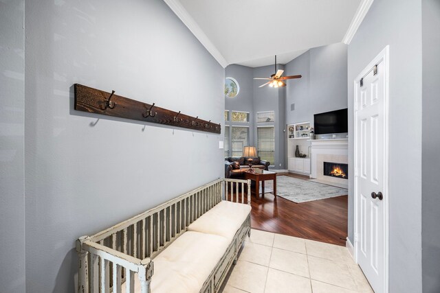 living room with high vaulted ceiling, crown molding, ceiling fan, and light hardwood / wood-style flooring