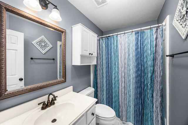 bathroom featuring vanity, a textured ceiling, toilet, and a shower with shower curtain