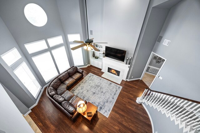 living room with ceiling fan, a towering ceiling, and dark hardwood / wood-style floors