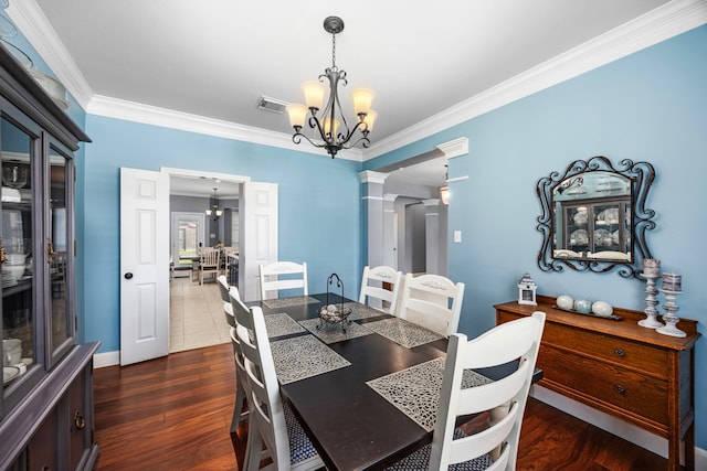 dining room featuring ornamental molding, decorative columns, a chandelier, and dark hardwood / wood-style floors