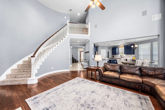 living room with hardwood / wood-style floors, ceiling fan with notable chandelier, and a towering ceiling