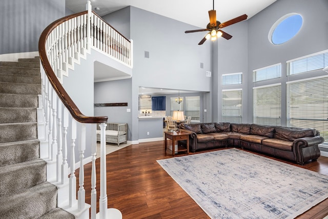 living room featuring ceiling fan, a towering ceiling, and dark hardwood / wood-style floors