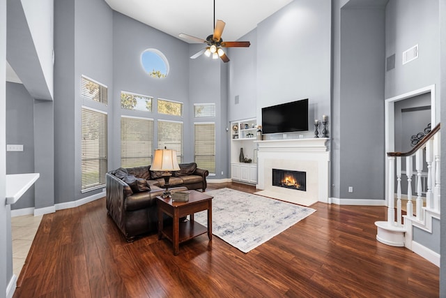 living room with a high ceiling, hardwood / wood-style floors, and ceiling fan