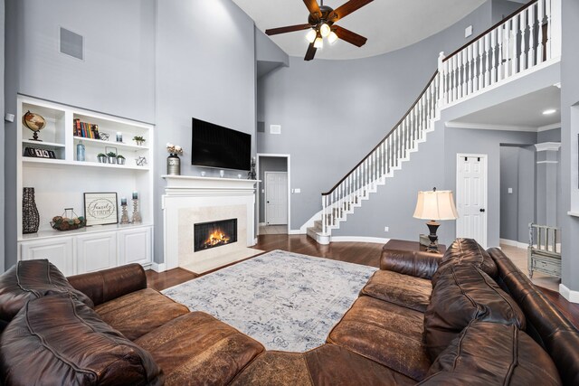 living room with a high ceiling, ornamental molding, a premium fireplace, decorative columns, and dark hardwood / wood-style flooring