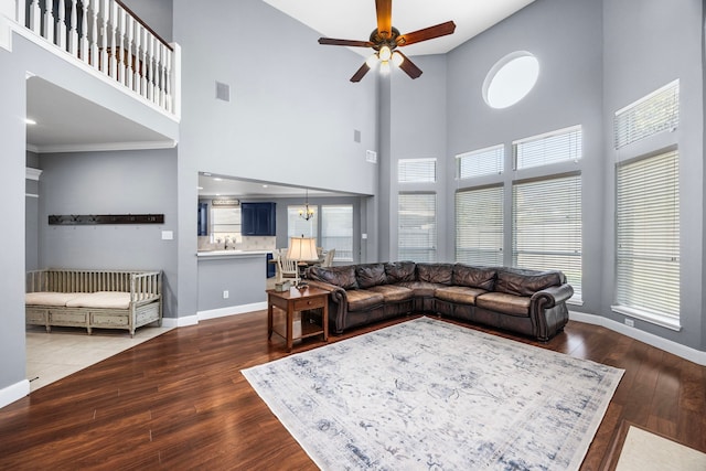 living room with a towering ceiling, ceiling fan with notable chandelier, and dark hardwood / wood-style floors