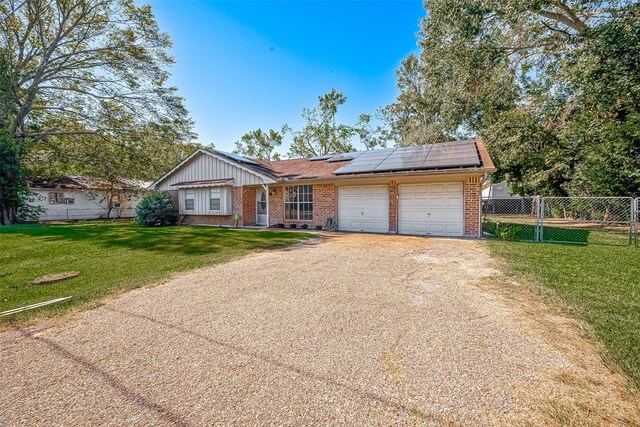 ranch-style house featuring a garage, solar panels, and a front lawn