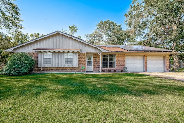 ranch-style house with a garage, a front yard, and solar panels