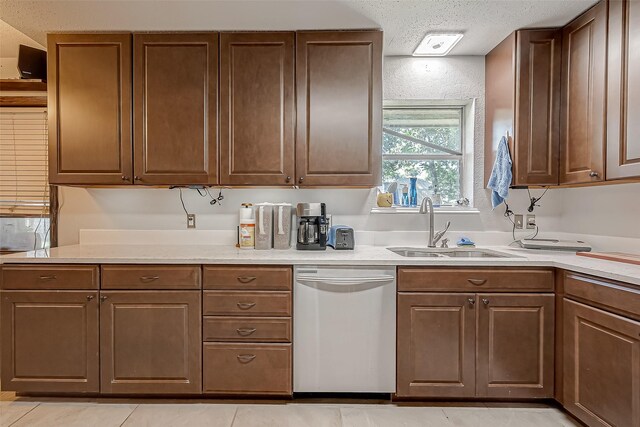 kitchen featuring light tile patterned floors, sink, stainless steel dishwasher, and a textured ceiling