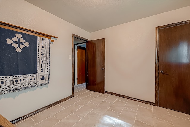 spare room featuring a textured ceiling and light tile patterned floors