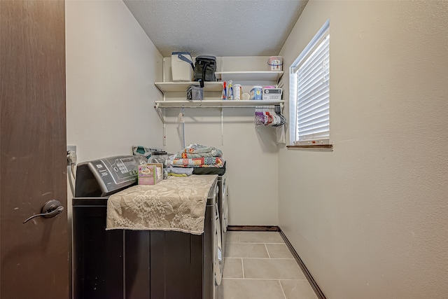 laundry room featuring washer and dryer, light tile patterned floors, and a textured ceiling