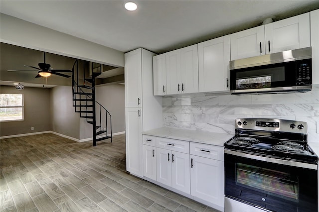 kitchen with white cabinets, tasteful backsplash, appliances with stainless steel finishes, light stone countertops, and light hardwood / wood-style floors