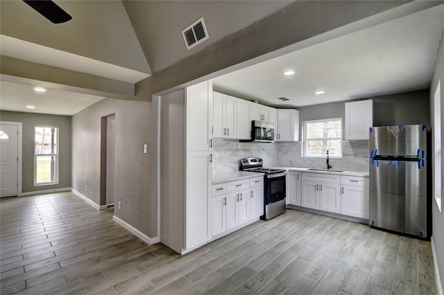 kitchen featuring a wealth of natural light, stainless steel appliances, and white cabinets