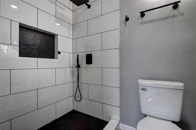 bathroom with tiled shower and toilet