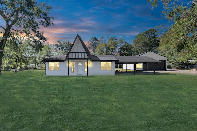 back house at dusk featuring a garage, a yard, and a carport