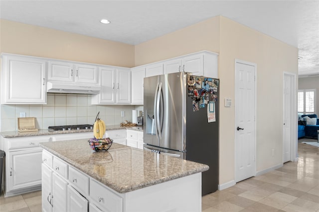 kitchen featuring light stone counters, decorative backsplash, a center island, white cabinetry, and appliances with stainless steel finishes