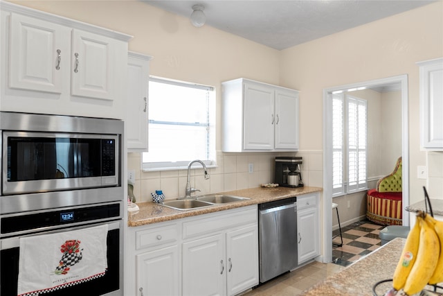 kitchen with tasteful backsplash, appliances with stainless steel finishes, sink, and white cabinetry