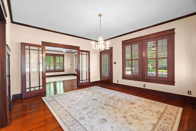 dining space featuring french doors, a chandelier, dark wood-type flooring, and crown molding