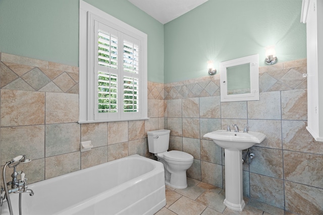 bathroom with tile patterned flooring, toilet, a bath, sink, and tile walls